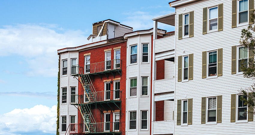 Three apartment buildings against a cloudy blue skyline