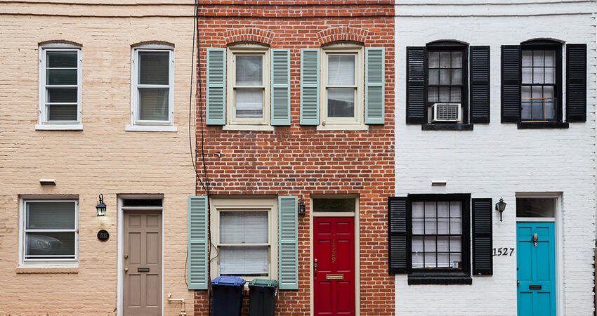A row of brick historic row houses with stoops and traditional windows along a residential street in Washington, D.C