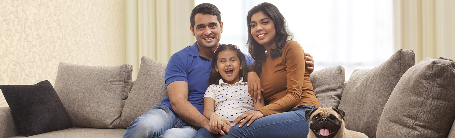 Parents sitting on couch with young daughter in the middle