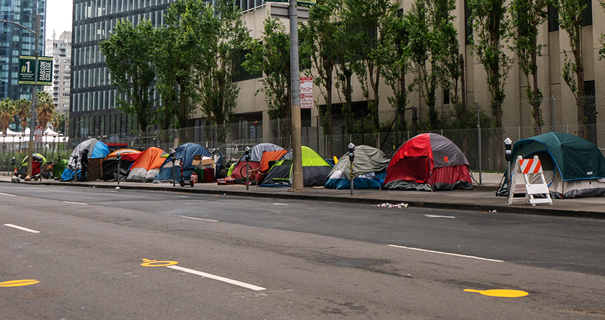 A line of tents on the side of a four lane road in a city