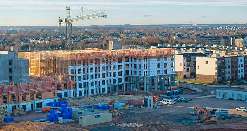 An aerial view of a large building under constriction in front of a gravel construciton site