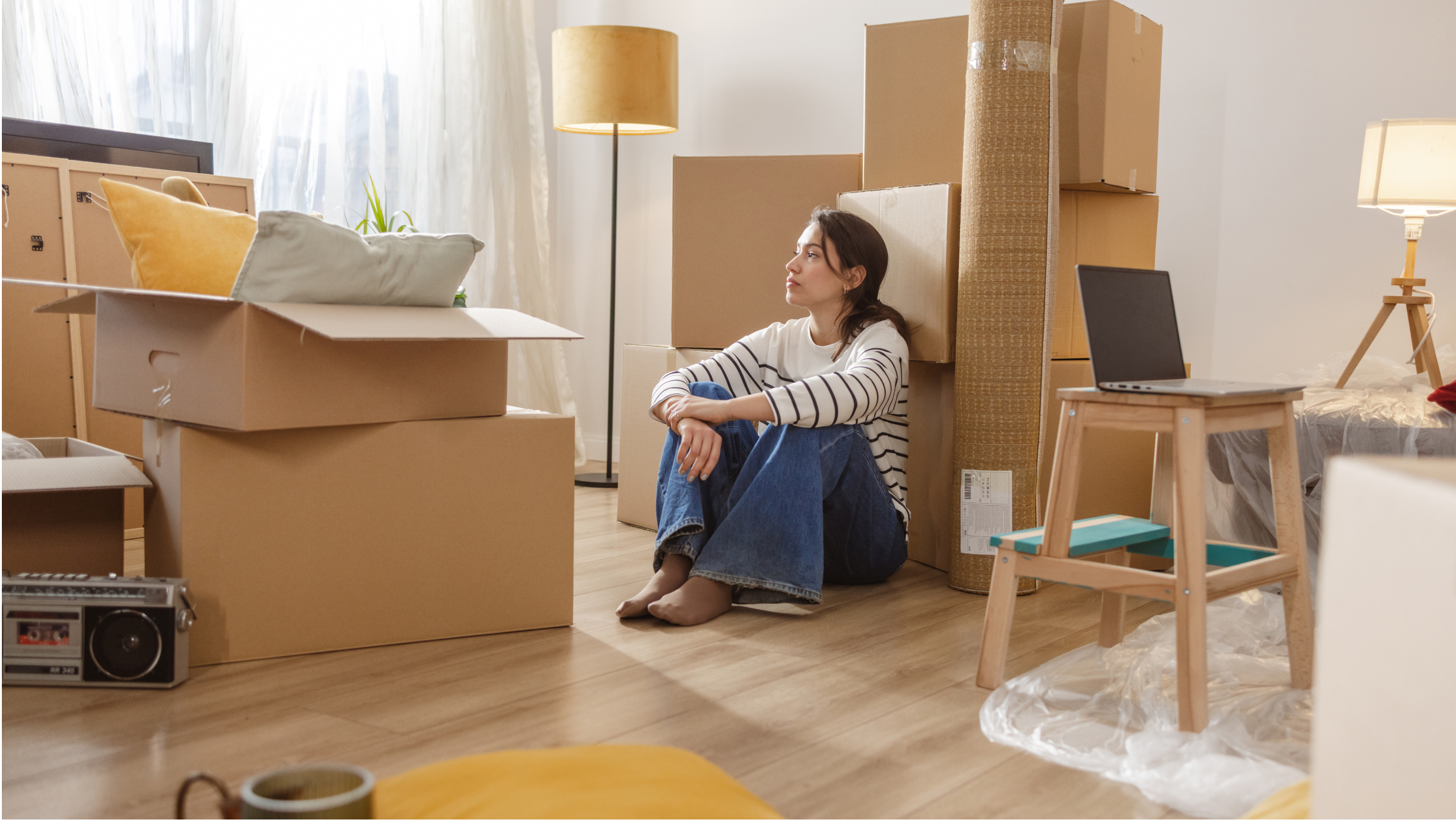 Person sitting among moving boxes in apartment.