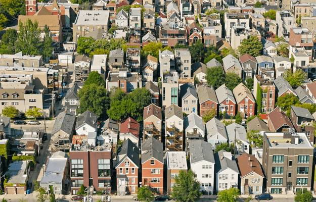 An aerial view of a dense neighborhood full of homes, apartment buildings, and trees