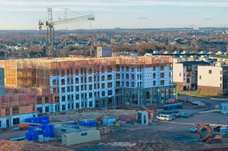 An aerial view of a large building under constriction in front of a gravel construciton site