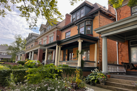 Row of historic brick houses with columned porches and a garden in front.