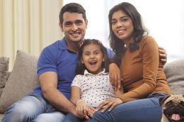Parents sitting on couch with young daughter in the middle