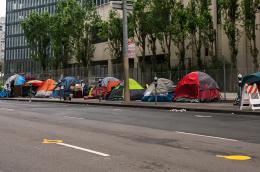 A line of tents on the side of a four lane road in a city